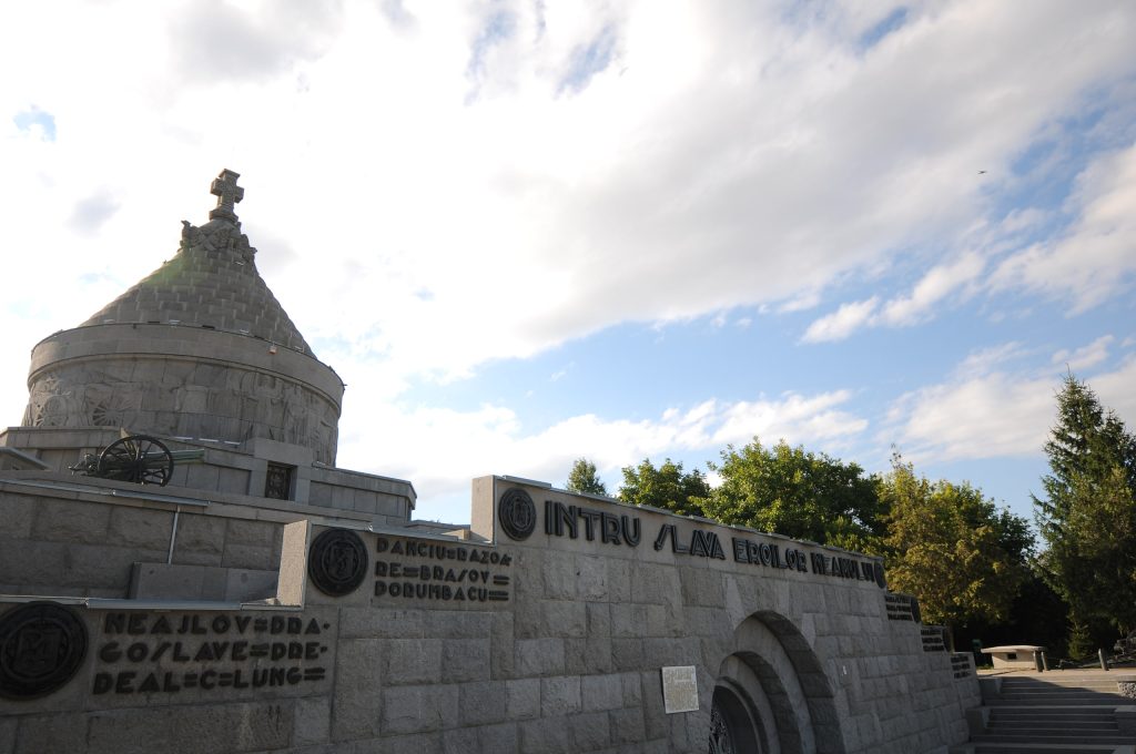 Stone mausoleum with a cross-topped dome, arched entrance, and commemorative inscriptions