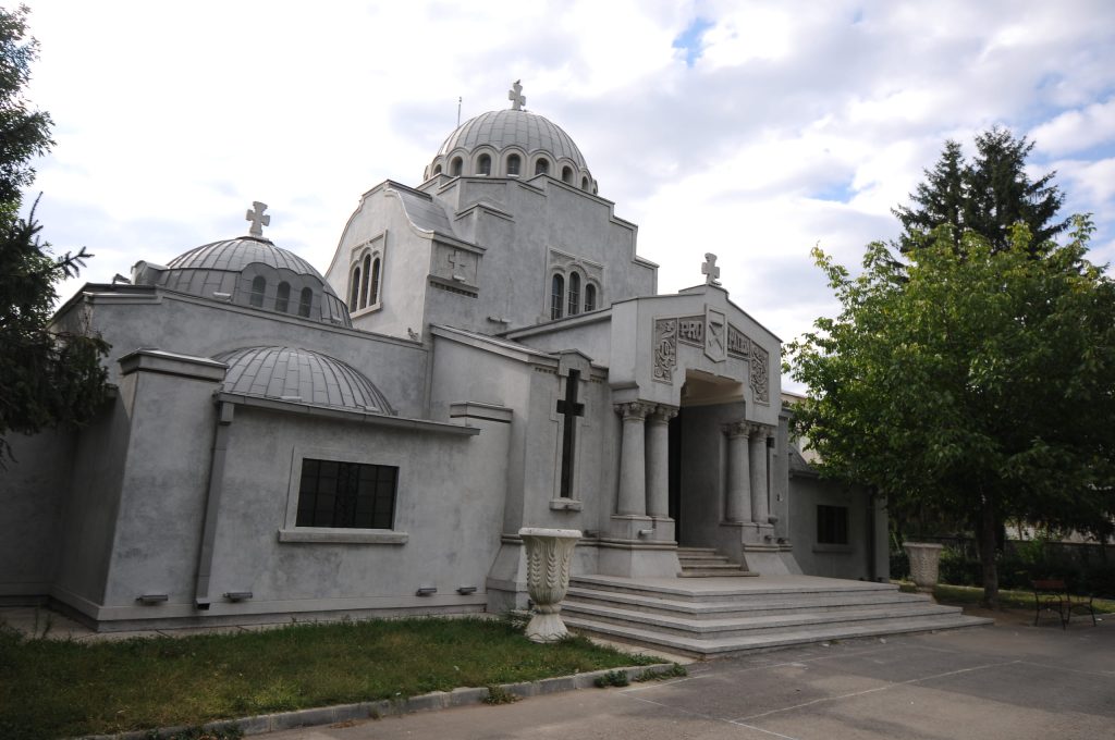 Grey stone mausoleum with multiple domes and steps at the entrance