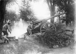 120 mm artillery gun firing beside a cemetery, operated by soldiers on the front