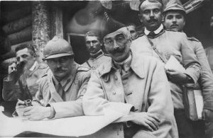 French and Romanian officers gathered at a command post around a table with a military map