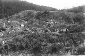 Military encampment with tents camouflaged with branches on a wooded slope