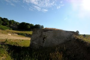 Concrete ruin of a water catchment basin in Mărăști, on a grassy slope under a clear sky