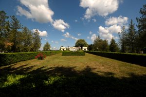 Distant frontal view of the Mărăști Mausoleum, with a grass lawn and trimmed hedges