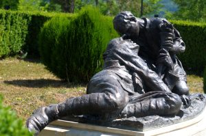 Bronze statue group depicting a wounded soldier held by a comrade, in the Mărăști Mausoleum park