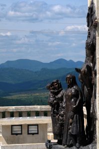 Bronze sculptural group at Mărăști Mausoleum, depicting women and children, with forested hills in background