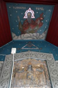 Mural painting showing the Eye of Providence and a religious scene above a carved frame