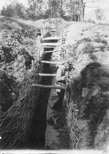 Soldier in an occupied enemy trench reinforced with wooden beams and wattle