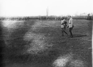 The King and General Averescu walking across a field in front of lined-up troops