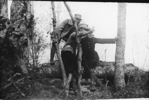 Three soldiers in military uniforms in a forest, one pointing forward with his finger