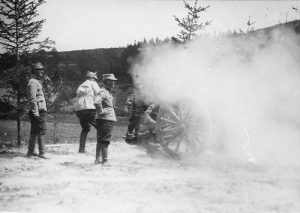 Soldiers firing a field artillery gun engulfed in a dense cloud of smoke
