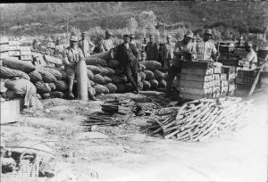 Soldiers and a civilian standing near artillery shells and ammunition crates
