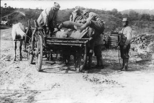 Soldiers unloading large artillery shells from a horse-drawn cart