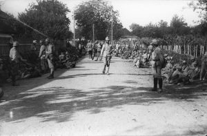 Romanian World War I soldiers on a village road, some resting along the roadside