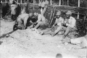 Romanian soldiers resting and eating next to a wattle fence on the First World War front