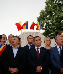 Officials and participants at the commemoration in front of tricolor flags