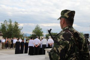 Soldier in camouflage uniform watching an outdoor religious service and choir