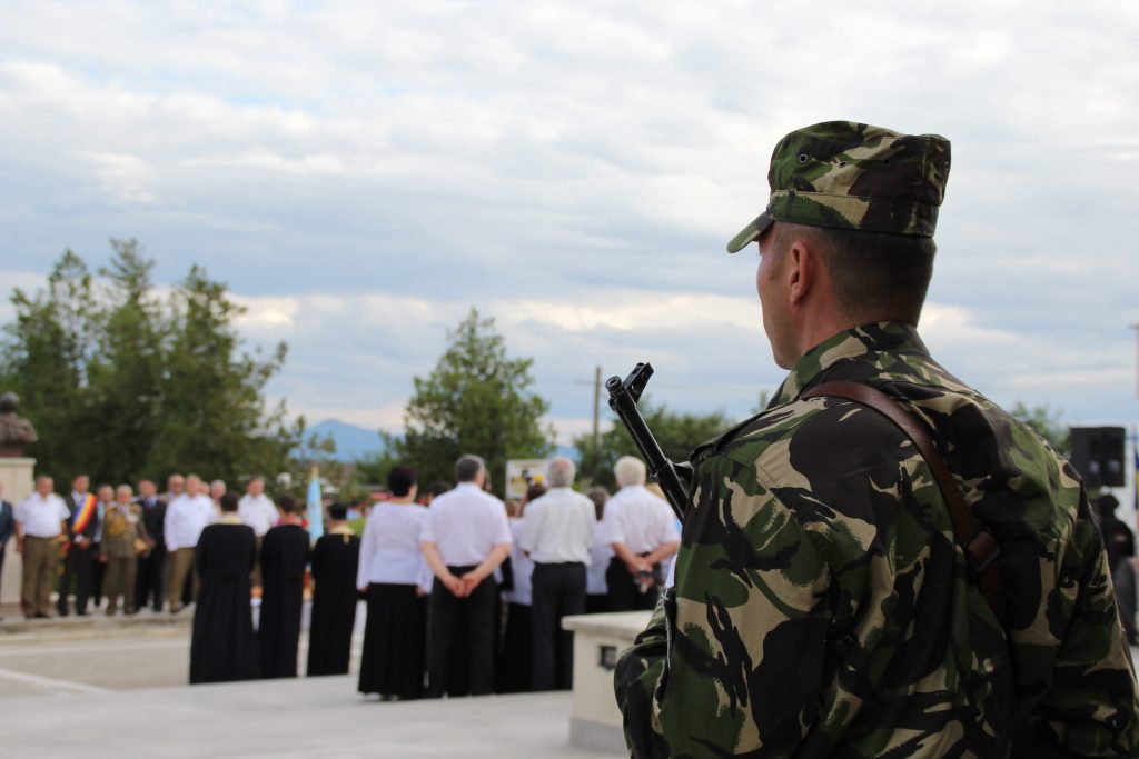 Soldier in camouflage uniform with a rifle on his shoulder attending a ceremony in Mărăști