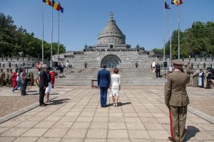 Princess Margareta and Prince Radu standing before the Mărășești Mausoleum, flanked by a saluting military officer