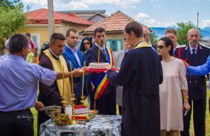 Priests and officials holding memorial coliva during an outdoor service in Mărăști
